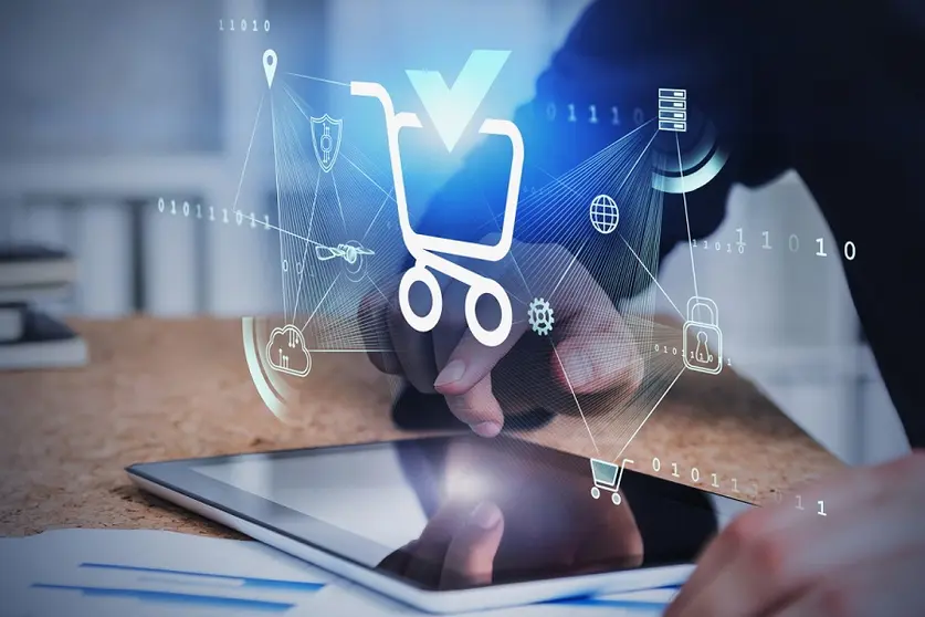 Hands of man using tablet in blurry office with double exposure of futuristic online shopping interface. Concept of ecommerce. Toned image