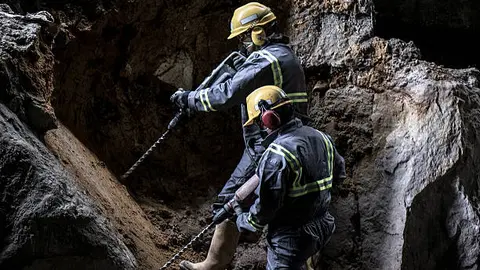 Two workers with helmet and protective suit using drill-machines in an underground enviroment